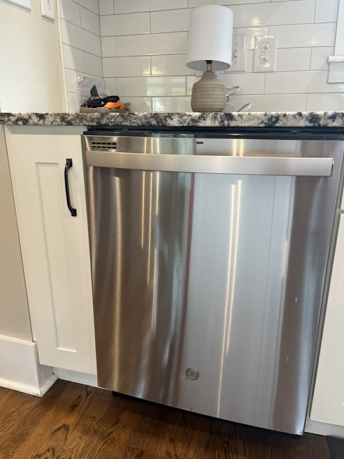 Clean stainless steel dishwasher with white shaker cabinets