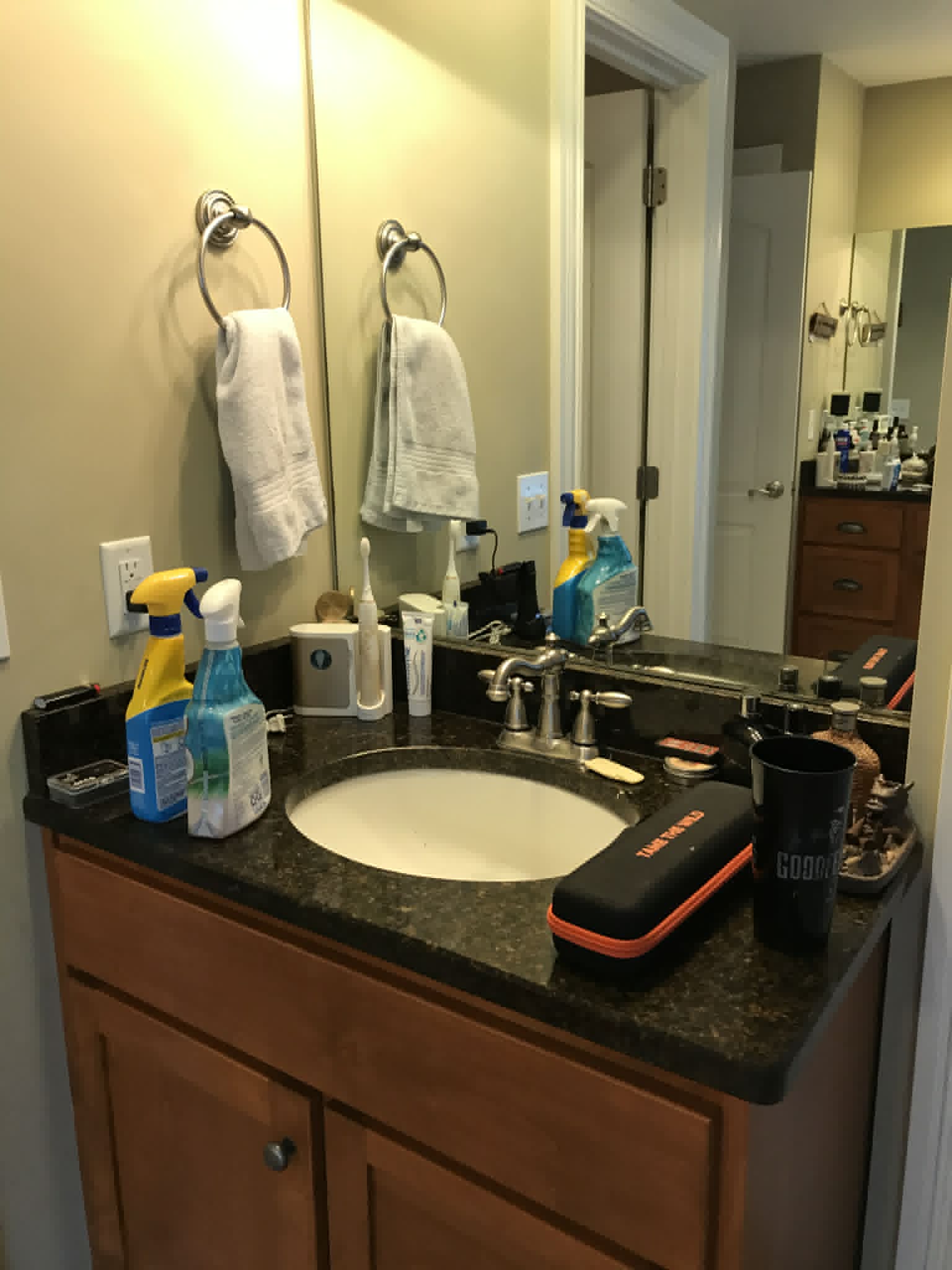 Bathroom vanity before — cluttered with products