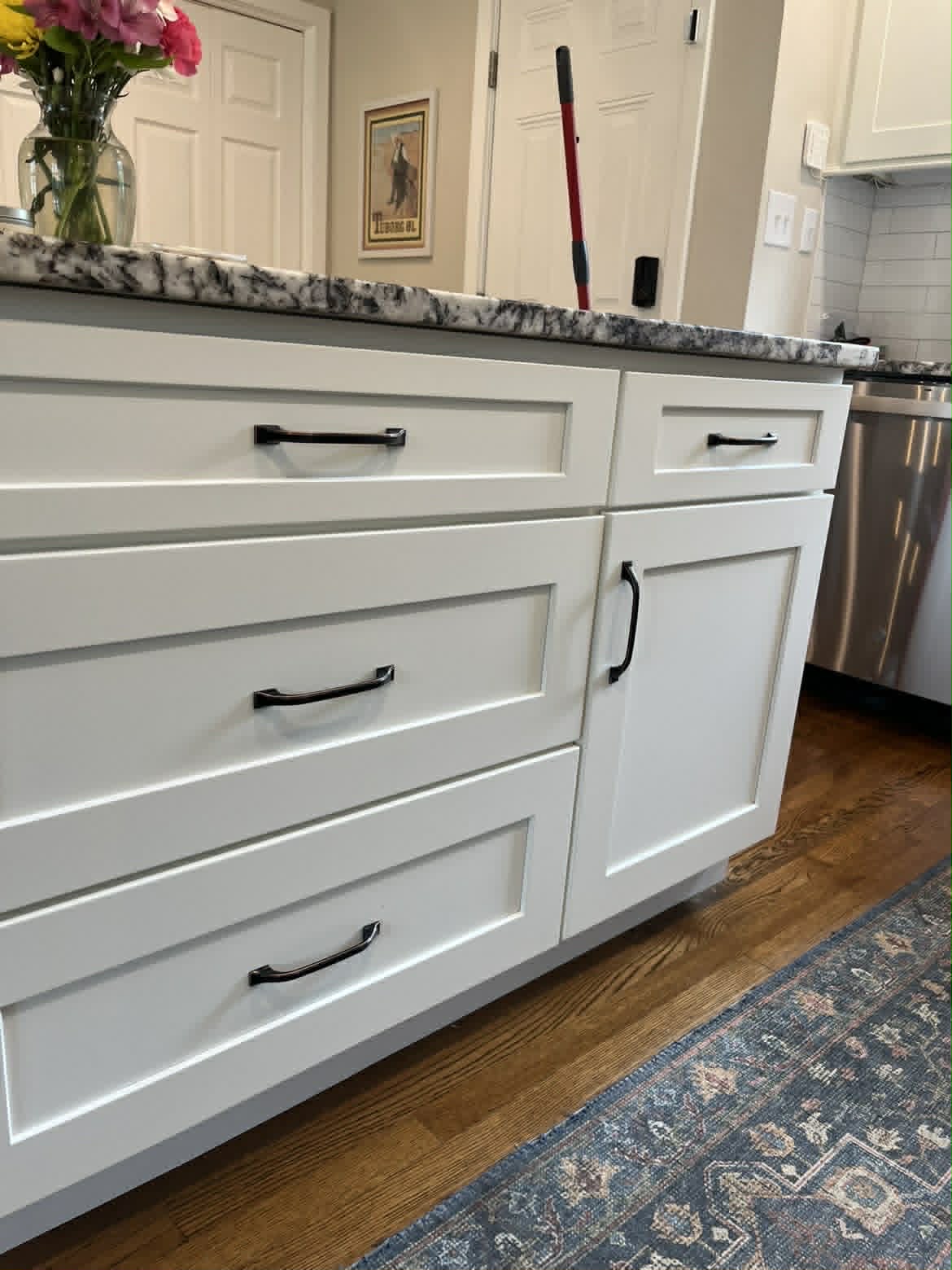 Clean white kitchen island drawers with granite counter